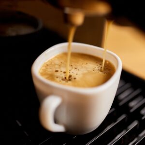 Detail of a professional coffe maker dripping coffe into an empty cup in a cafeteria