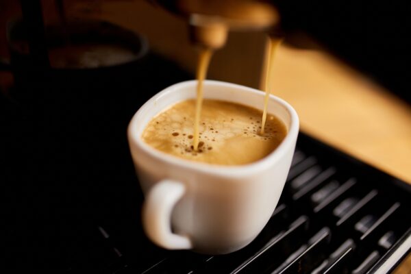 Detail of a professional coffe maker dripping coffe into an empty cup in a cafeteria